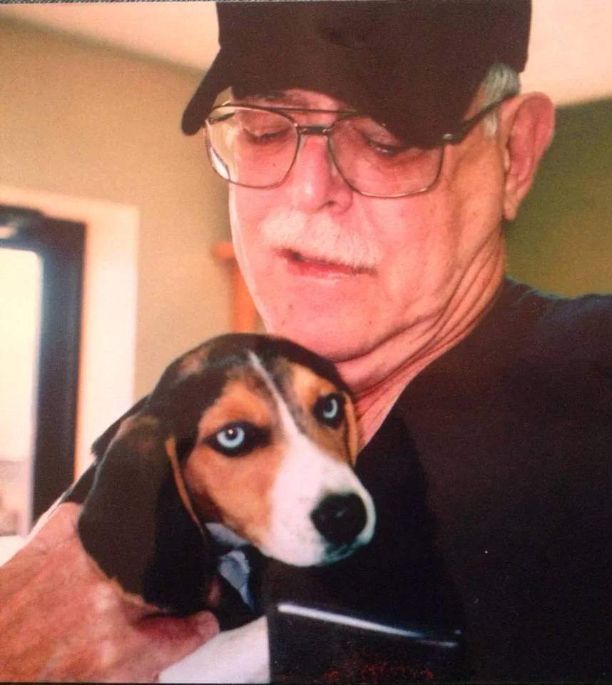 An older man in a cap holding a puppy
